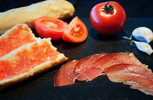 a table topped with meat and tomatoes and bread at Ibis Lleida in Lleida