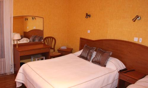 a bedroom with a bed and a desk and a mirror at Logis Hôtel & Restaurant Aux Tauzins in Montfort-en-Chalosse