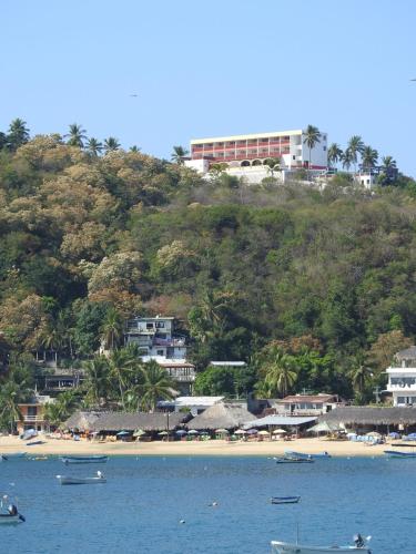 a beach with boats in the water and buildings on a hill at Angel del Mar in Puerto Ángel