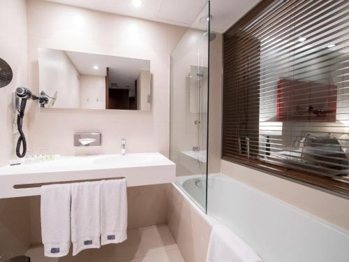 a bathroom with a shower, sink, and mirror at Hotel Carris Porto Ribeira in Porto