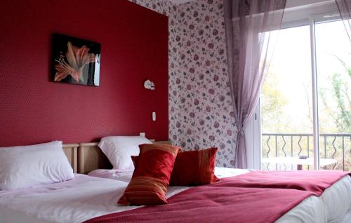 a bedroom with two beds with red walls and a window at Logis Hôtel & Restaurant Aux Tauzins in Montfort-en-Chalosse
