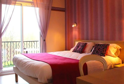 a bedroom with a bed with a large window at Logis Hôtel & Restaurant Aux Tauzins in Montfort-en-Chalosse