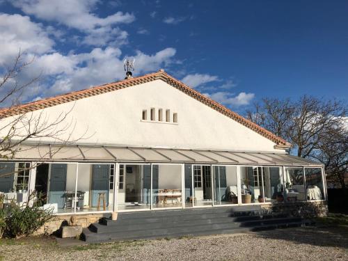 une maison blanche avec une véranda et des fenêtres dans l'établissement Aux Belles Vacances - ADULTS ONLY, à Caux-et-Sauzens