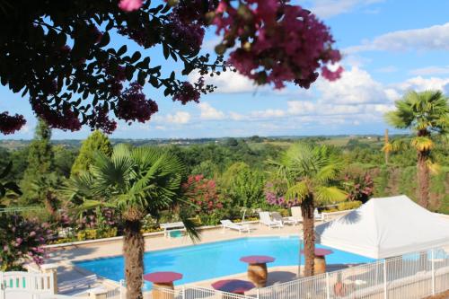 a resort with a pool and palm trees at Logis Hôtel & Restaurant Aux Tauzins in Montfort-en-Chalosse