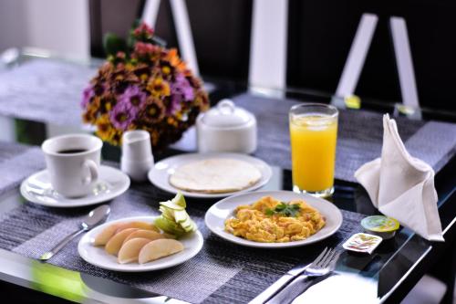 stół z talerzami jedzenia i szklanką soku pomarańczowego w obiekcie Hotel Flamingo Cali w mieście Cali