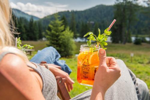 a woman holding a jar of honey with a plant in it at Ludlalm am Prebersee in Tamsweg