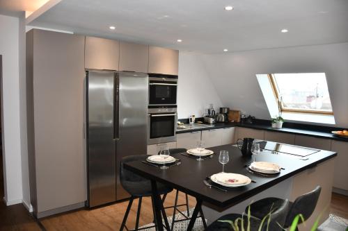 eine Küche mit einem Tisch und einem Kühlschrank aus Edelstahl in der Unterkunft L'Ecrin des Saveurs in Schwenheim