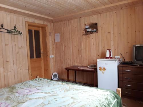 - une chambre avec un lit, une télévision et un réfrigérateur dans l'établissement Яблуневий сад, à Yablunytsya