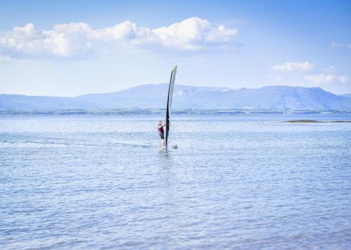 a person standing on a surfboard in the water at MacKays in Oban