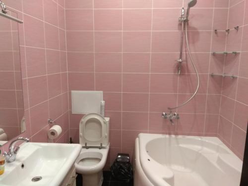 un bagno rosa con vasca, servizi igienici e lavandino di Apartment on Sobornaya street a Rivne
