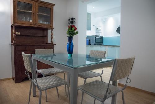 Una mesa de comedor con sillas y un jarrón con flores. en La casa in Camollia, en Siena