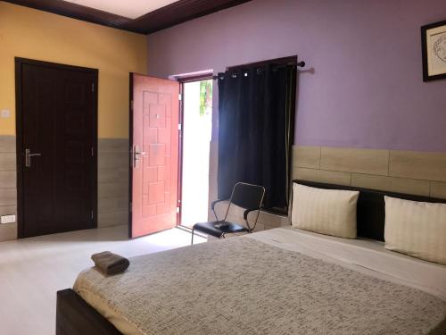 a bedroom with a bed with a pink door and a chair at Omanye Lodge in Accra