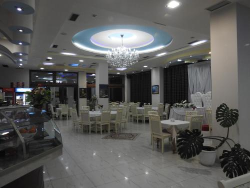 restauracja z białymi stołami i krzesłami oraz żyrandolem w obiekcie Hotel 3 Vellezerit w Durrës