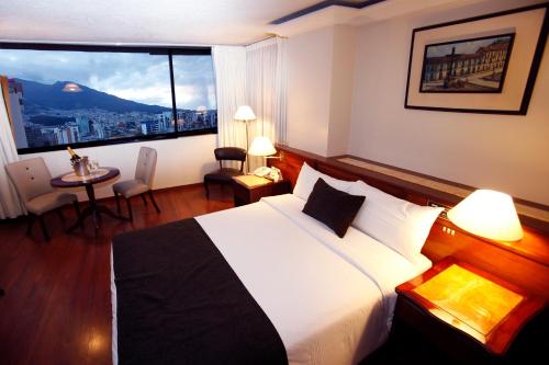 um quarto de hotel com uma cama e uma grande janela em Hotel Reina Isabel em Quito