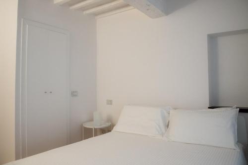 a white bedroom with a bed with white pillows at La casa in Camollia in Siena