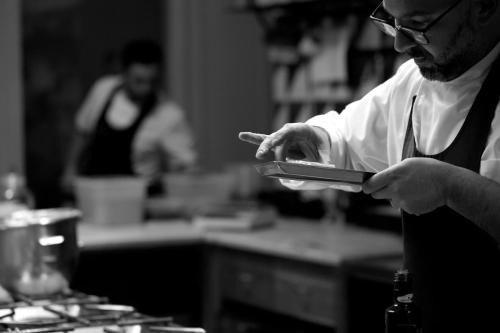 a man in a kitchen holding a cell phone at La Foresteria Planetaestate in Menfi