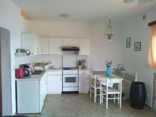 Apartment Djanina في كريس: مطبخ مع دواليب بيضاء وطاولة وكراسي
