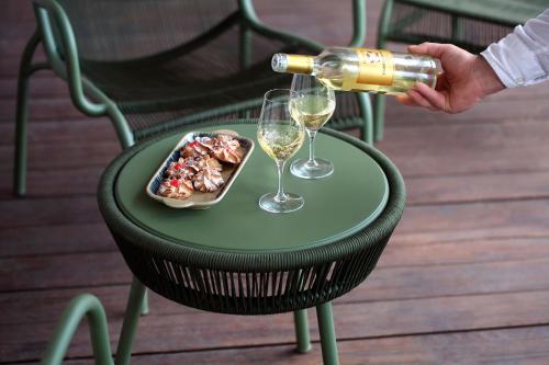 a person pouring wine into glasses on a table with food at La Foresteria Planetaestate in Menfi