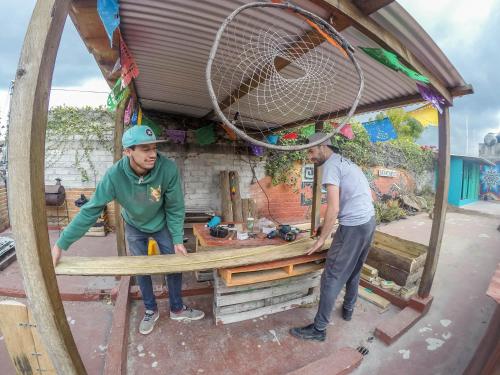 due uomini stanno lavorando su un tavolo di legno di Hostel El Nagual a San Cristóbal de Las Casas