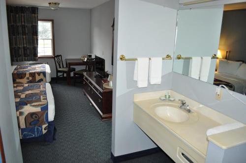 ein Bad mit einem Waschbecken und ein Bett in einem Zimmer in der Unterkunft Grand Islander Hotel in Put-in-Bay