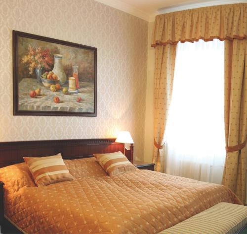 a bedroom with a bed and a painting on the wall at Hotel Kolonada in Karlovy Vary