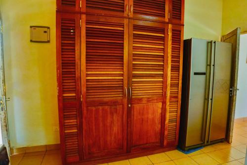 a wooden cabinet next to a refrigerator in a room at Upani in Diani in Diani Beach