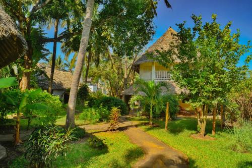 a house in the middle of a garden with trees at Upani in Diani in Diani Beach