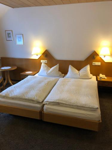 - une chambre dotée d'un grand lit avec des draps et des oreillers blancs dans l'établissement Hotel-Restaurant Gasthof zum Schützen, à Baiersbronn