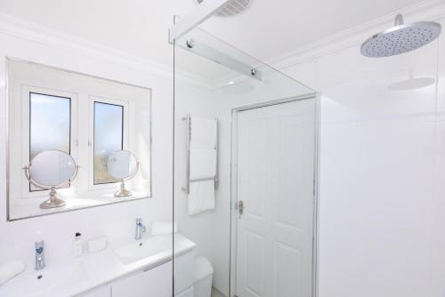 a white bathroom with two sinks and a shower at Villa on Camps Bay Drive in Cape Town