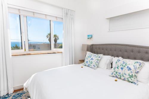 a white bedroom with a large bed with a window at Villa on Camps Bay Drive in Cape Town