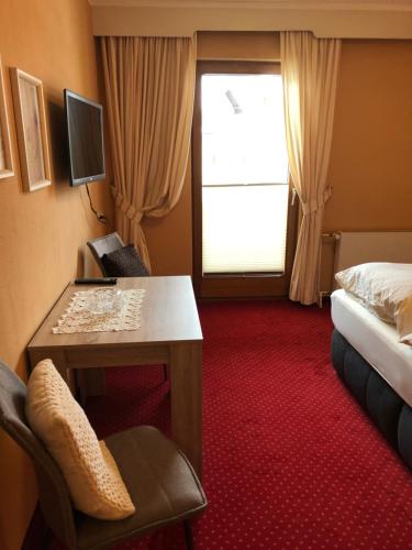 a hotel room with a desk and a bed and a window at Hotel-Restaurant Gasthof zum Schützen in Baiersbronn