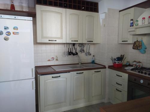 a kitchen with white cabinets and a white refrigerator at Villetta Simo in Capilungo