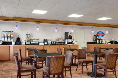 a restaurant with tables and chairs and a kitchen at Baymont by Wyndham Elizabethtown in Elizabethtown