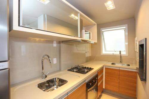 una piccola cucina con lavello e fornello di Apartamento com Piscina no Centro e a poucos metros do mar de Torres -RS a Torres