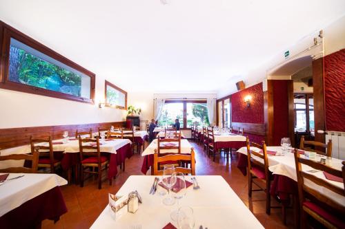 a restaurant with white tables and chairs and windows at Hotel Ristorante Il Caminetto in Diano Marina