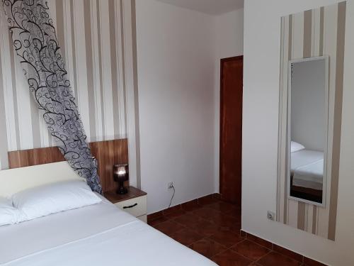 a bedroom with a white bed and a mirror at Apartments Taida in Dobra Voda