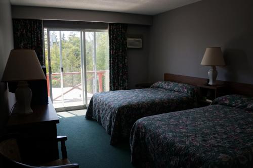 a hotel room with two beds and a window at Tobermory Inn & Suites in Tobermory