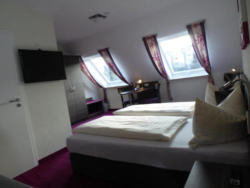 a bedroom with two beds and a flat screen tv at Pension am Weinberg Bed & Breakfast in Mainstockheim