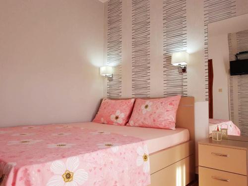 Un dormitorio con una cama rosa con sábanas rosas y blancas. en Apartments Taida en Dobra Voda