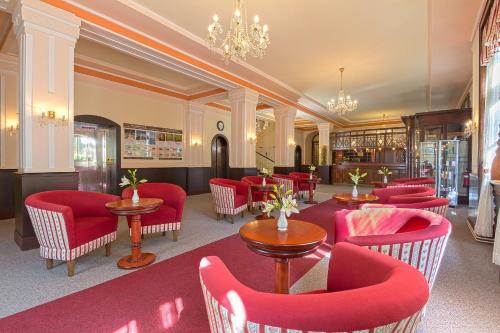 a restaurant with red chairs and tables in a room at Belvedere Spa & Kurhotel in Františkovy Lázně