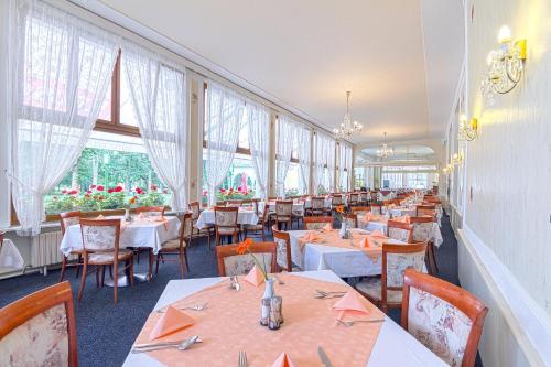 a dining room with tables and chairs and windows at Belvedere Spa & Kurhotel in Františkovy Lázně