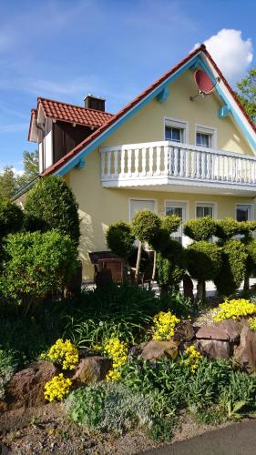 a white house with a white balcony and some flowers at Ferienwohnung am Waldchen in Bad Kissingen