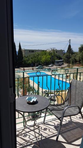 a balcony with a table and chairs and a swimming pool at Maria Studios in Paleokastritsa