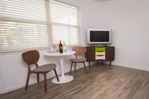 a living room with a table and chairs and a tv at Regency Inn & Suites Sarasota in Sarasota