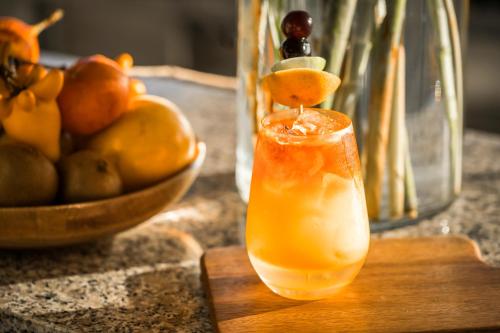 a drink on a cutting board with a bowl of fruit at Aranwa Paracas Resort & Spa in Paracas