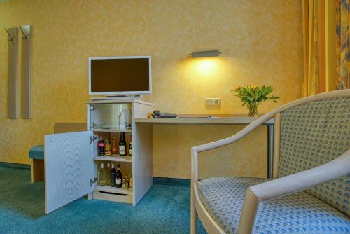a room with a desk with a tv and a chair at Hotel Kischers Landhaus in Hannover