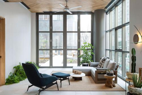 a living room with a ceiling fan and large windows at ROOST East Market in Philadelphia