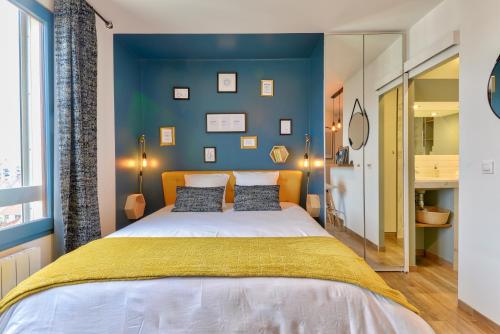 une chambre avec un grand lit et un mur bleu dans l'établissement Home Chic Home - Studio Paris La Défense - Les Toits de Courbevoie, à Courbevoie