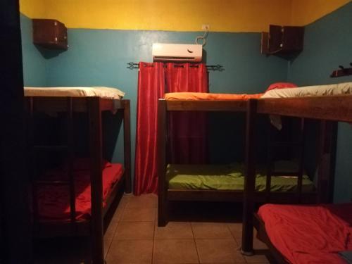 a room with three bunk beds and a red curtain at Cliff's Hostel in La Gruta
