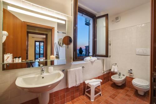 W łazience znajduje się umywalka, toaleta i lustro. w obiekcie Appartamenti La Grotta w mieście Bardolino